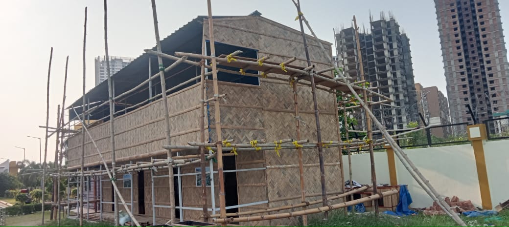 Corner view of the nearly complete habitat wrapped in scaffolding, New Town high-rises in the background
